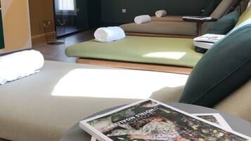 Une salle de spa moderne avec une table de massage, des serviettes et un magazine posé sur une table ronde.