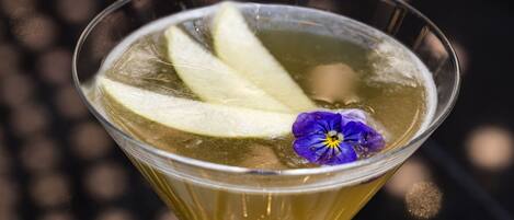 Un verre à martini contenant un liquide transparent, des glaçons et une fleur violette en guise de décoration.