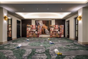 A spacious lobby with a large abstract painting, exercise mats, and dumbbells on the floor.