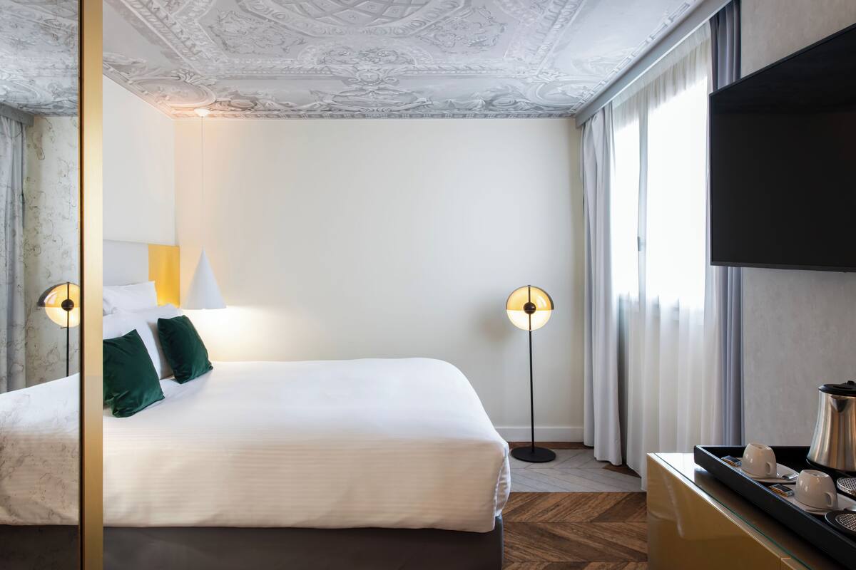 Une chambre d’hôtel avec un grand lit, deux lampes de chevet, un téléviseur à écran plat et un coin café.