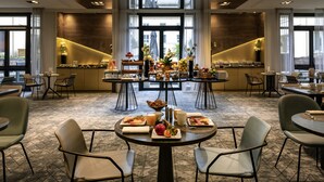 Un vaste espace dédié à la salle à manger, doté de nombreuses tables et chaises, avec une table centrale où sont disposés divers plats et un centre de table décoratif.