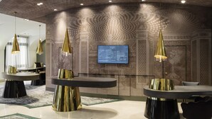 Un intérieur moderne avec un plafond incurvé, un papier peint à motifs et des luminaires suspendus dorés.