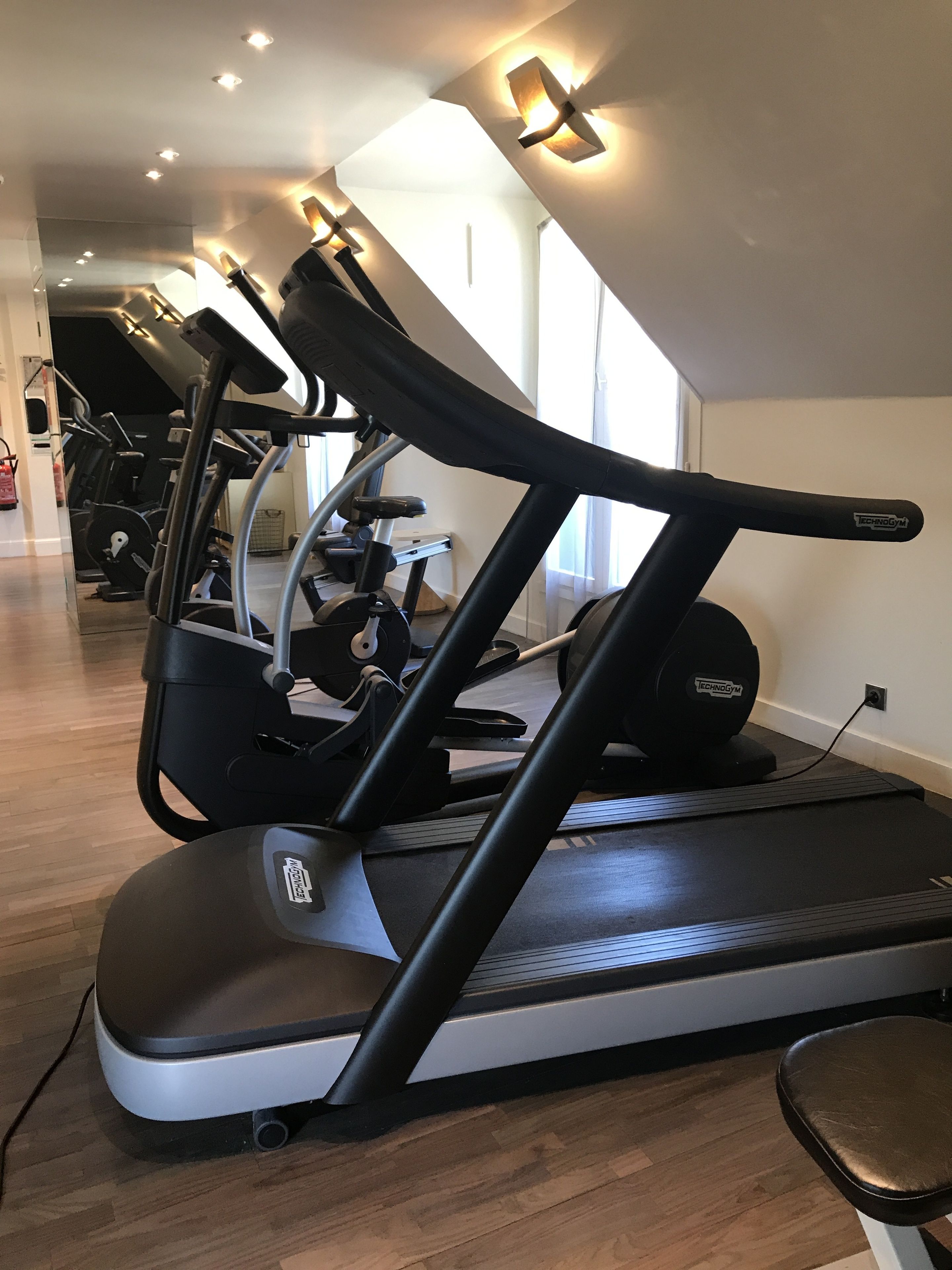 Een sportschool met meerdere loopbanden, een roeimachine en een hometrainer.