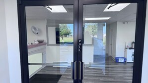 A modern office entrance with a glass door, a pull handle, and a "PULL" sign. - Florence Inn and Suites (Florence)