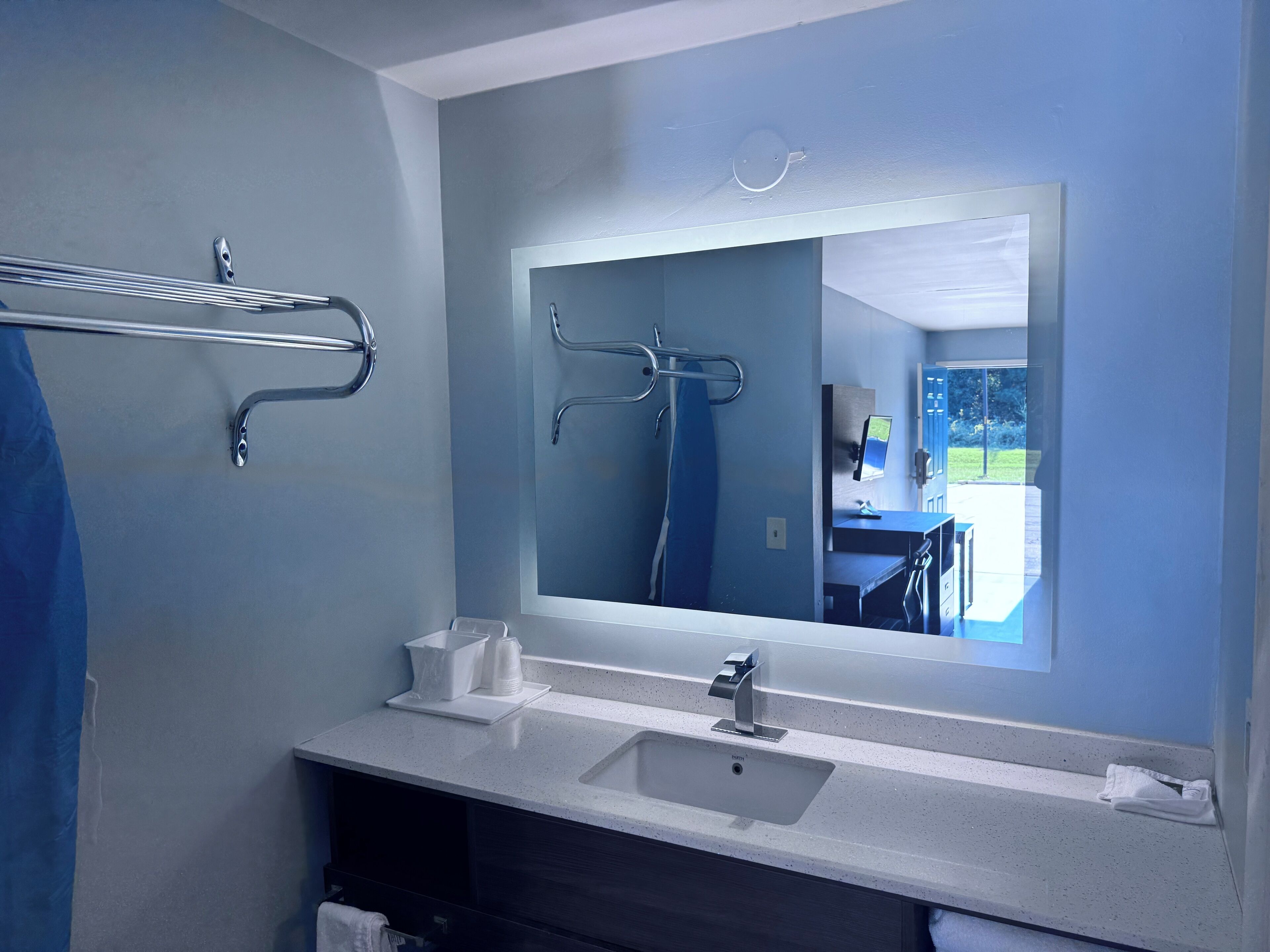 Un baño moderno con un espejo grande, un lavabo y un perchero para toallas.