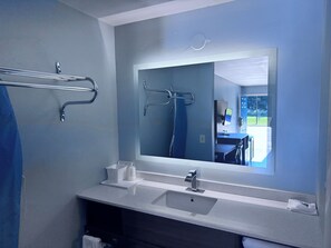 A modern bathroom with a large mirror, a sink, and a towel rack.