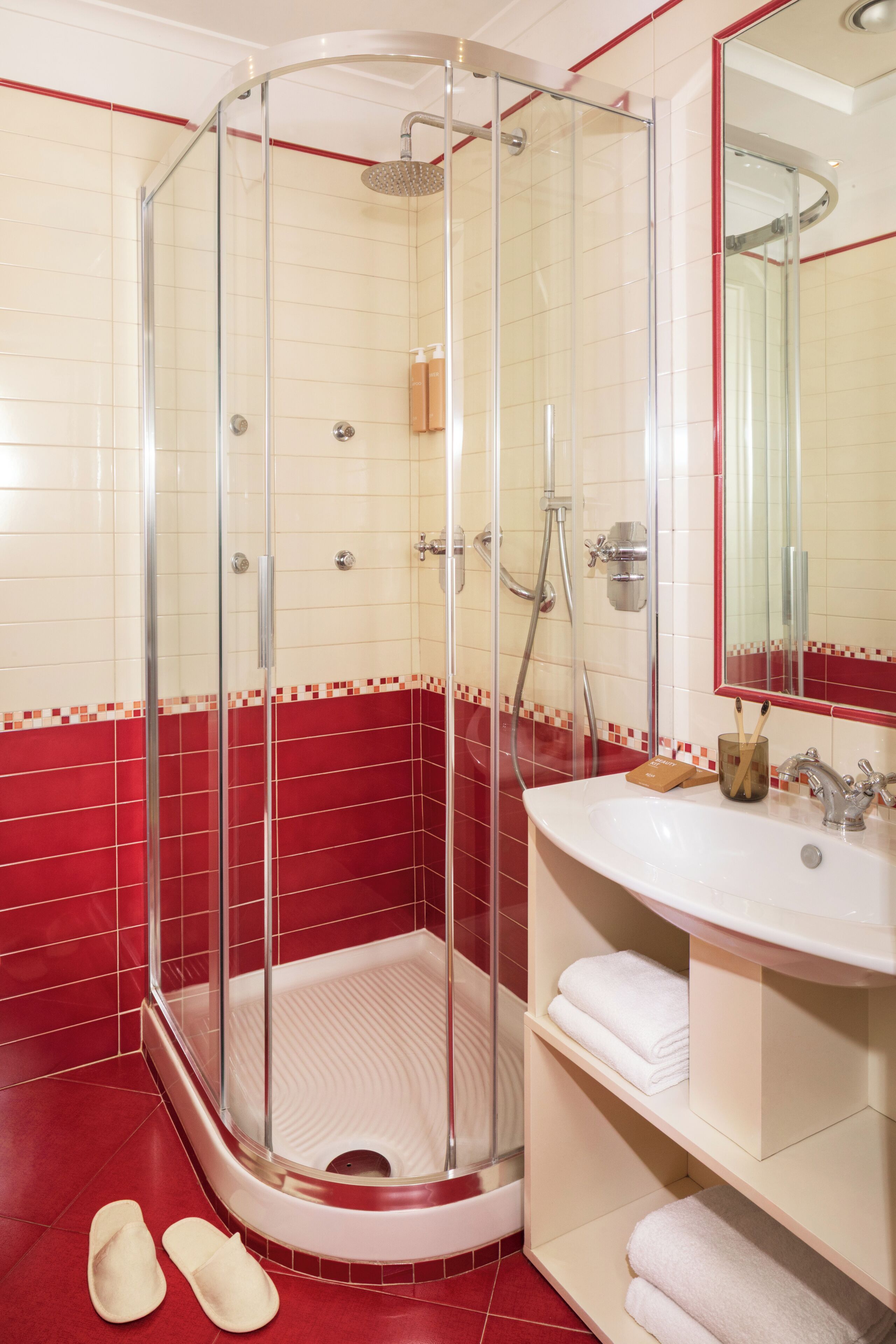A bathroom with a glass-enclosed shower, a white sink, and a mirror.