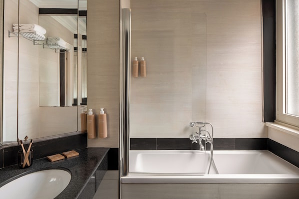 Un baño moderno con un espejo grande, una bañera y una ducha.