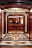 A reception area with a marble floor, wooden reception desk, and a receptionist.