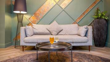 A modern living room with a grey sofa, a round coffee table, a floor lamp, and a large potted plant.
