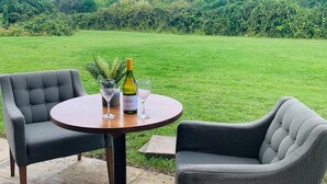 An outdoor seating area with two grey upholstered chairs and a round table, featuring a bottle of wine and glasses. - Mercure Cardiff (Cardiff)