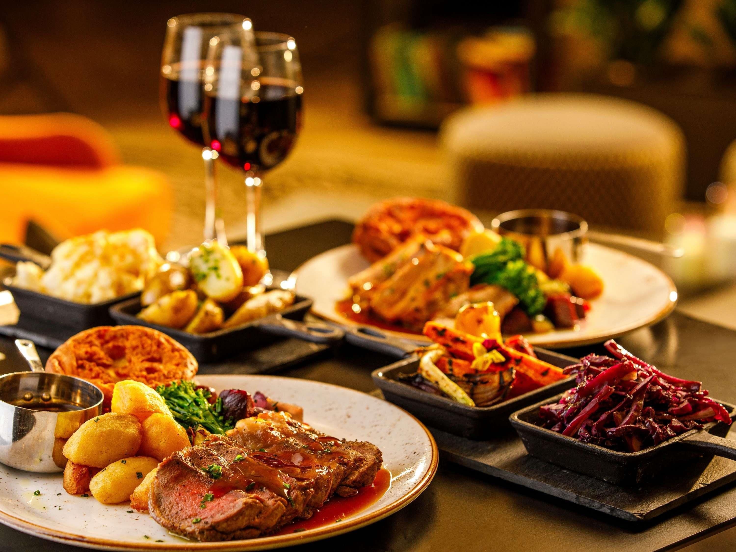 Une variété de plats présentés sur des assiettes, un verre de vin rouge et une bougie, le tout dans un décor de salle à manger.