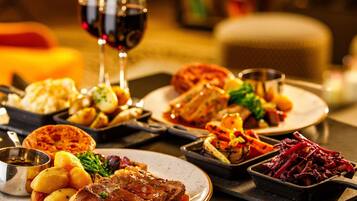 Une variété de plats présentés sur des assiettes, un verre de vin rouge et une bougie, le tout dans un décor de salle à manger.