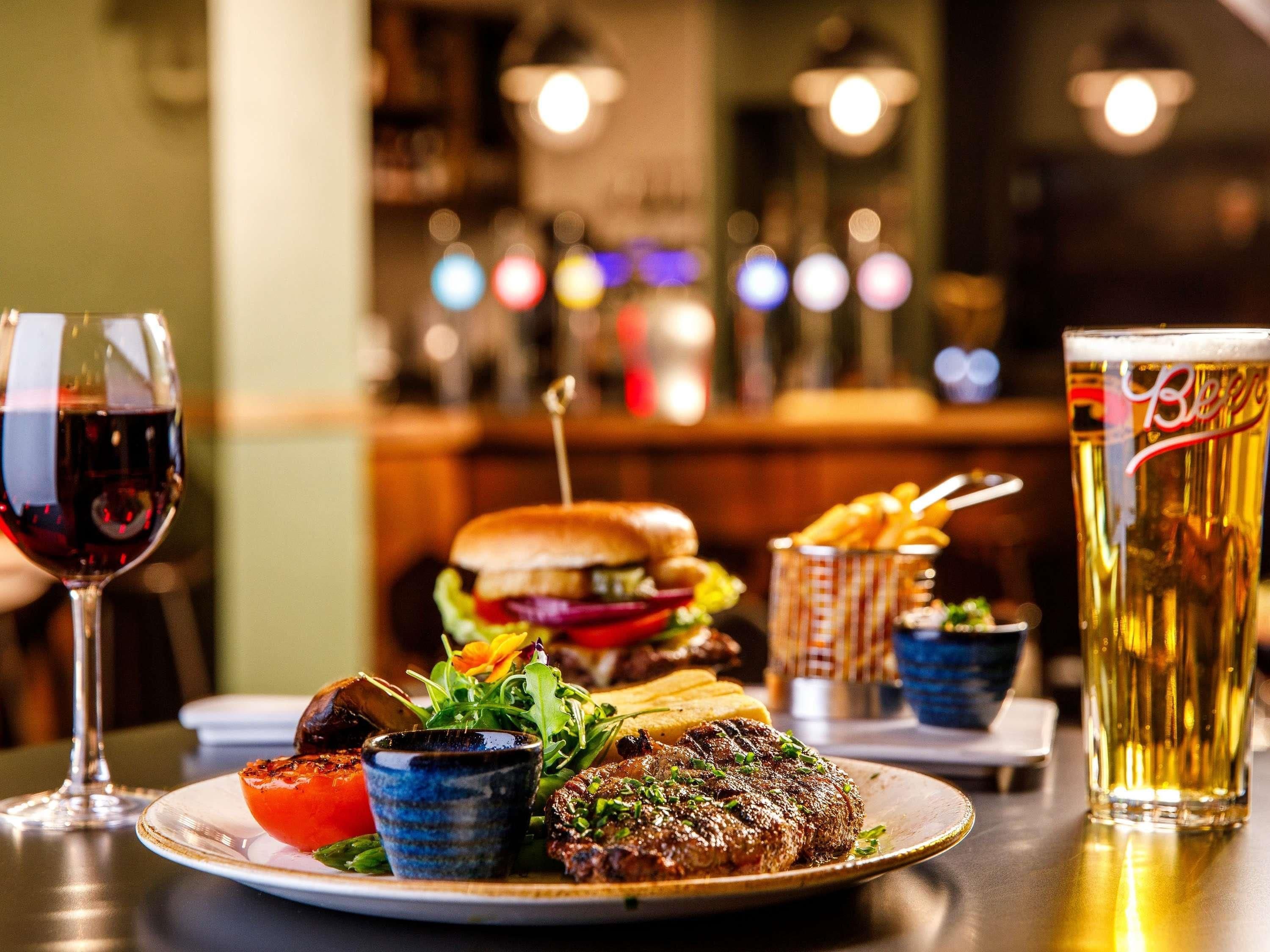 Uma mesa de jantar com um prato de comida, um copo de cerveja e uma taça de vinho.