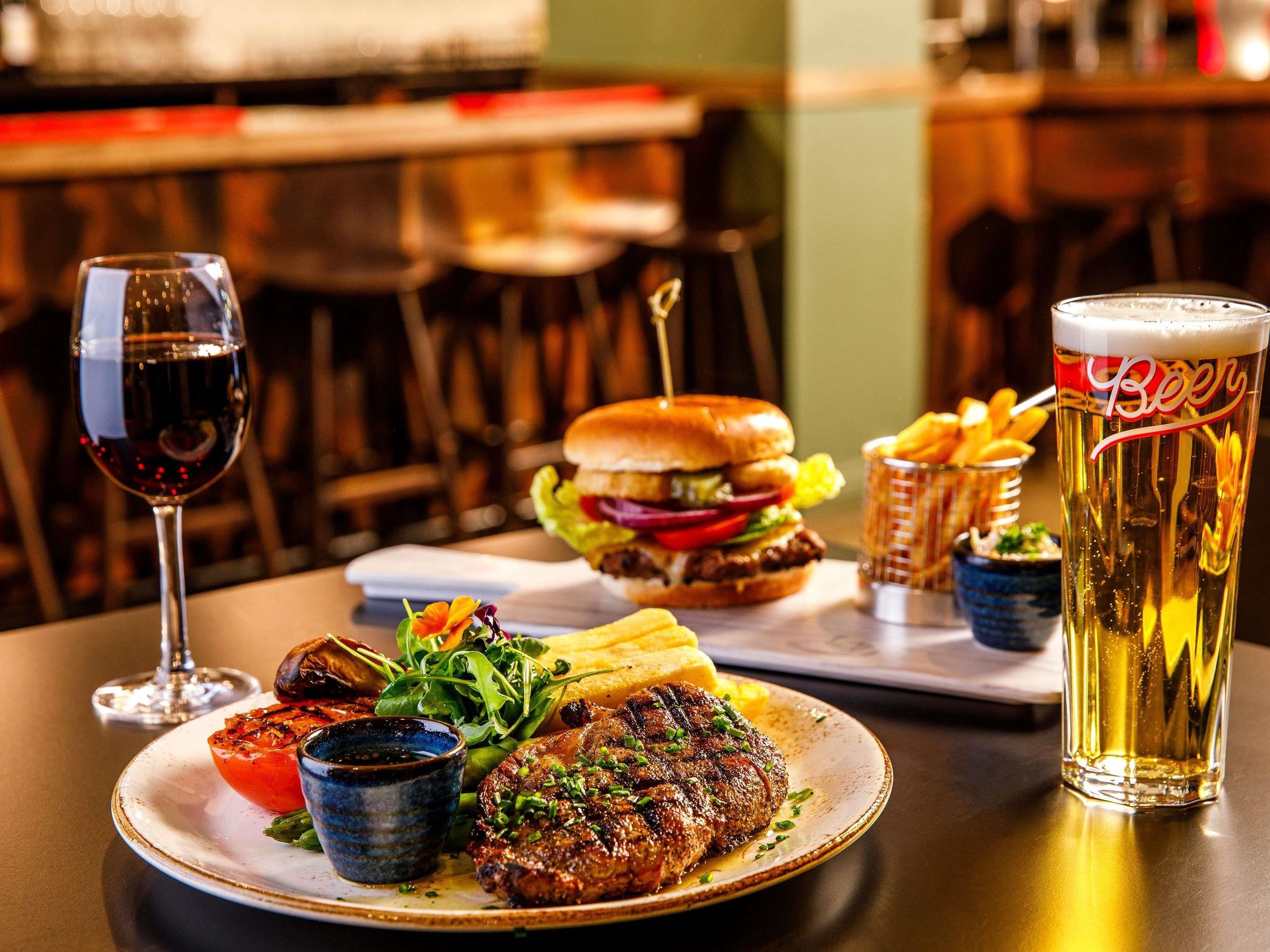 Een maaltijd met een hamburger, friet en een glas bier op een tafel.