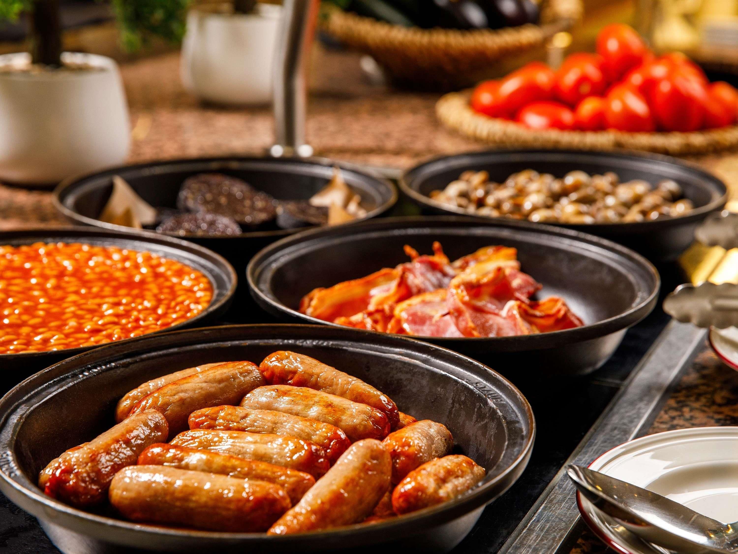 Un assortiment de plats comprenant des saucisses, des haricots et des tomates.