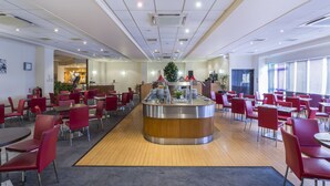 A spacious cafeteria with red chairs and a central food display. - Mercure Cardiff (Cardiff)