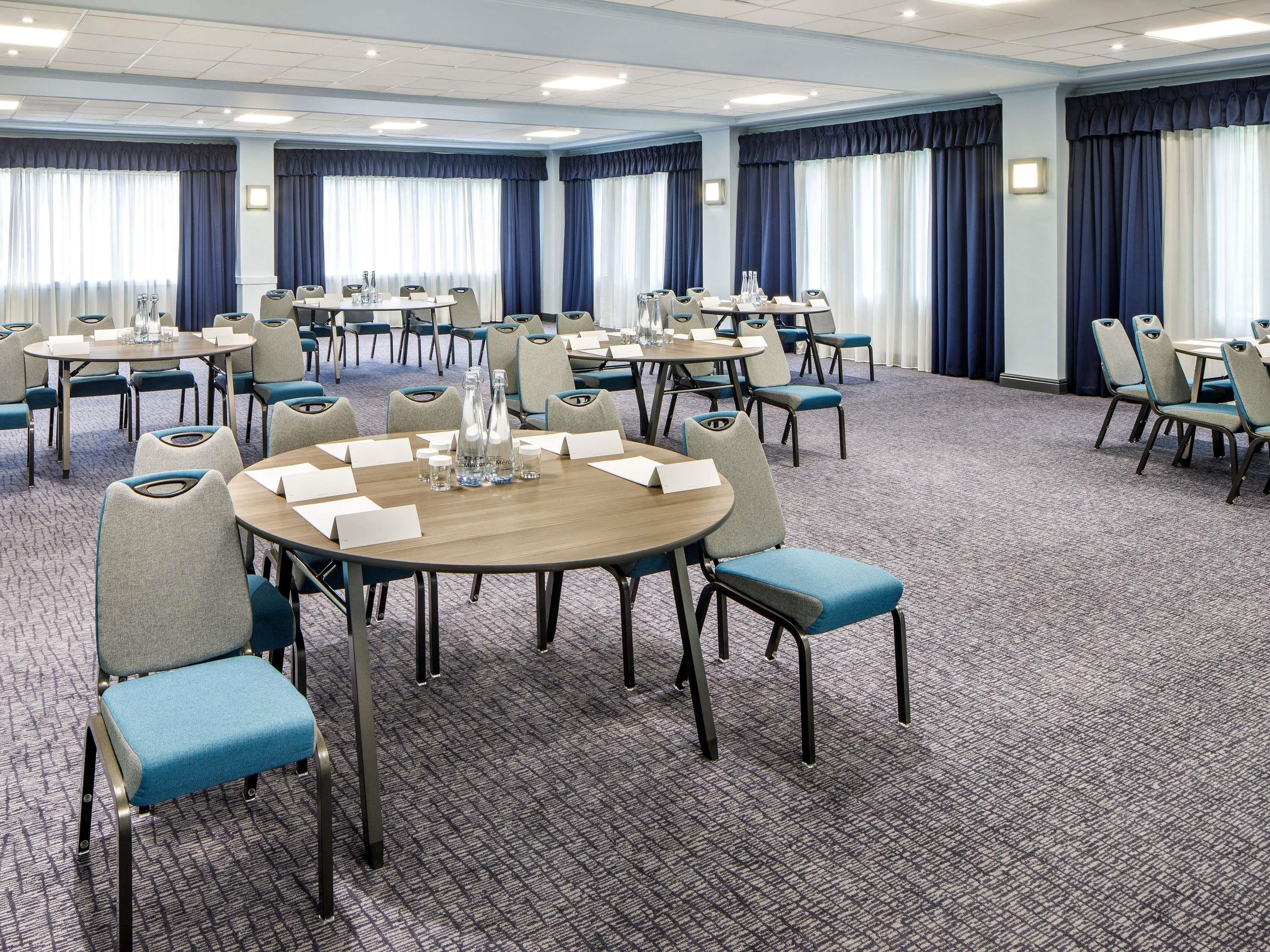 A conference room with round tables, chairs, and water bottles.