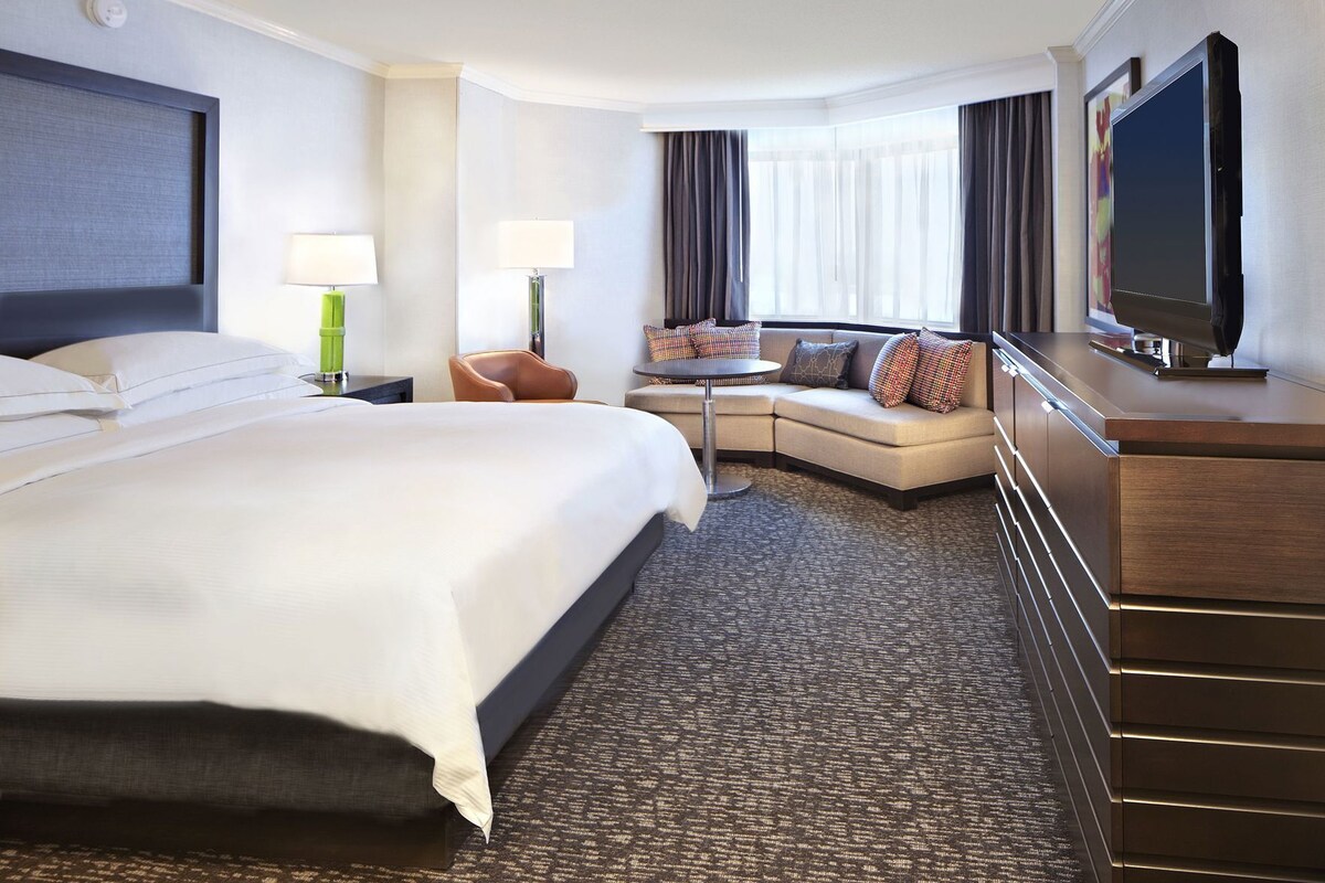 Une chambre d’hôtel avec un grand lit, un canapé, un bureau et un téléviseur à écran plat.
