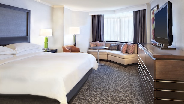 Une chambre d’hôtel avec un grand lit, un canapé, une télévision et un bureau.