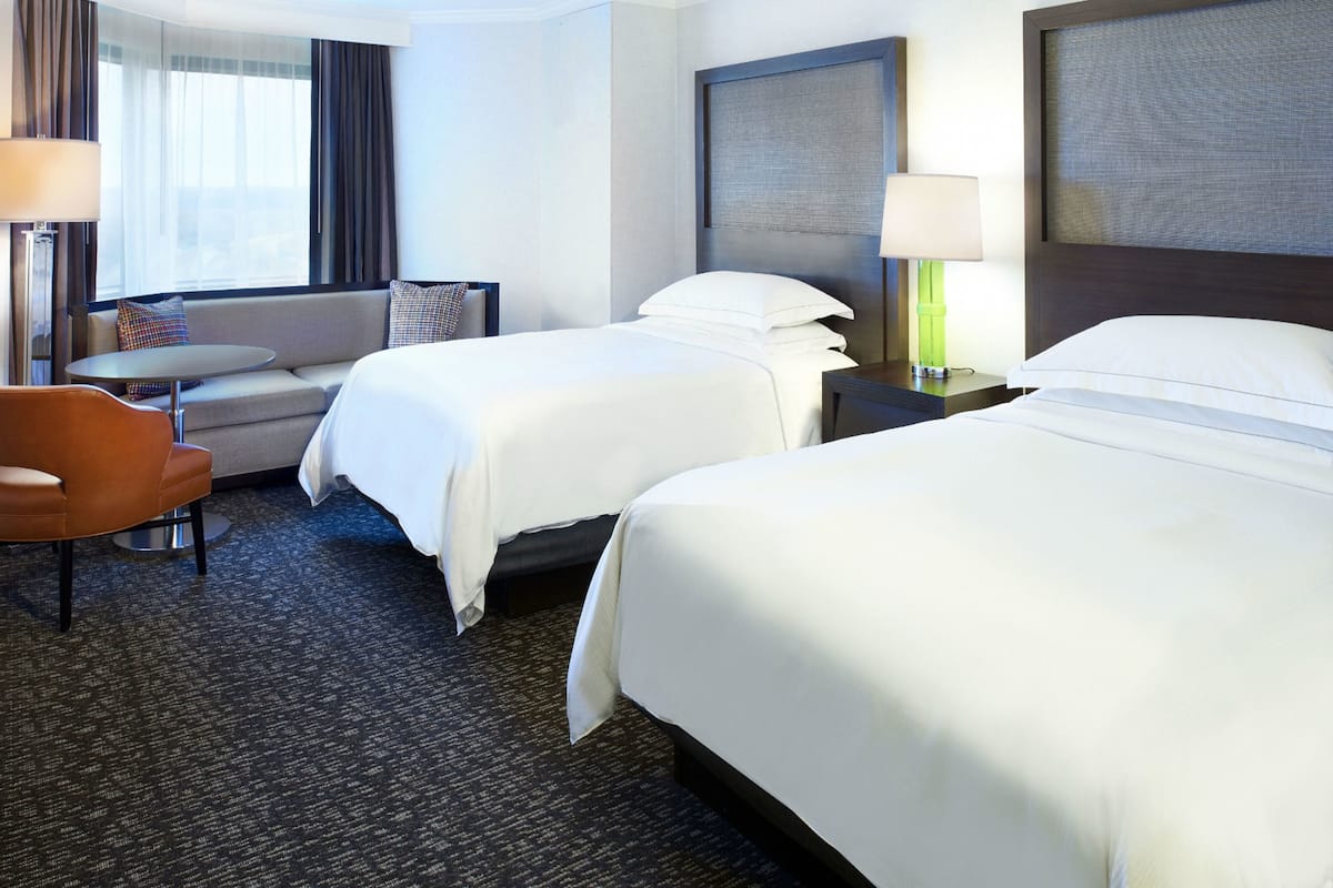 Une chambre d’hôtel avec deux lits, un canapé, une petite table et une chaise.