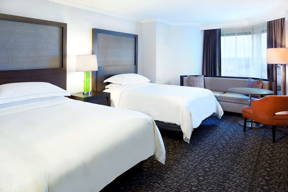 Une chambre d’hôtel avec deux lits, un canapé, une petite table et une chaise.