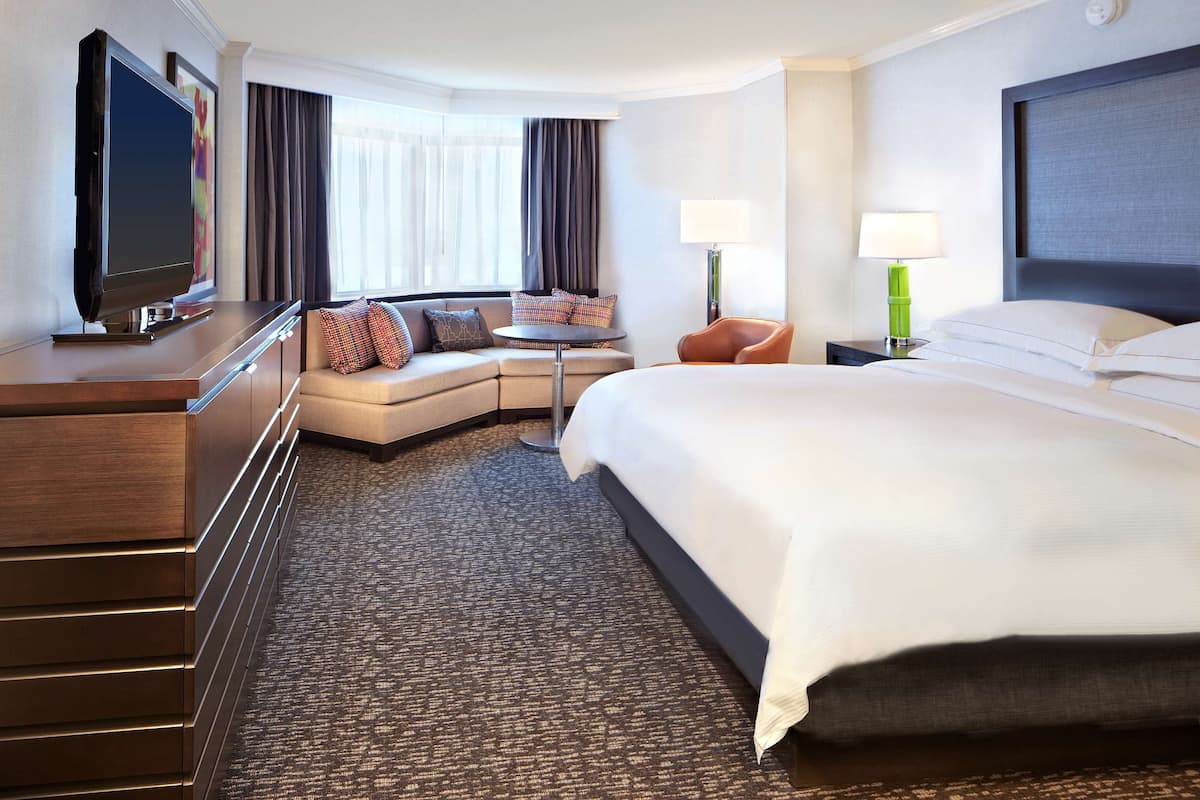 Une chambre d’hôtel avec un grand lit, un canapé, une télévision et un bureau.