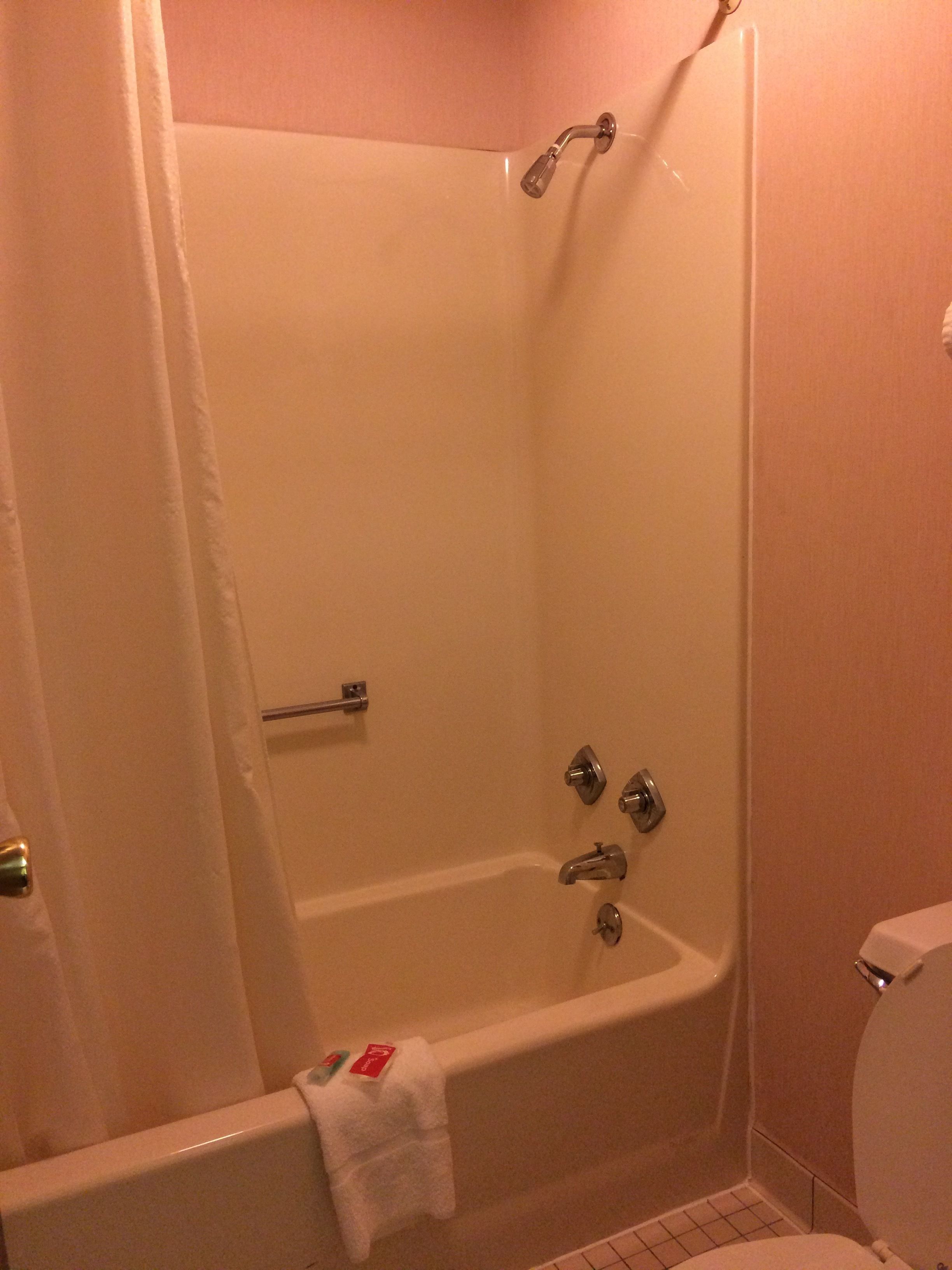 Een standaard badkamer met bad, toilet en douchegordijn.