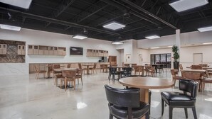 A spacious indoor area with multiple tables and chairs, a high ceiling with exposed beams, and built-in cabinets. - Cottonwood Suites Savannah Hotel & Conference Center (Pooler)