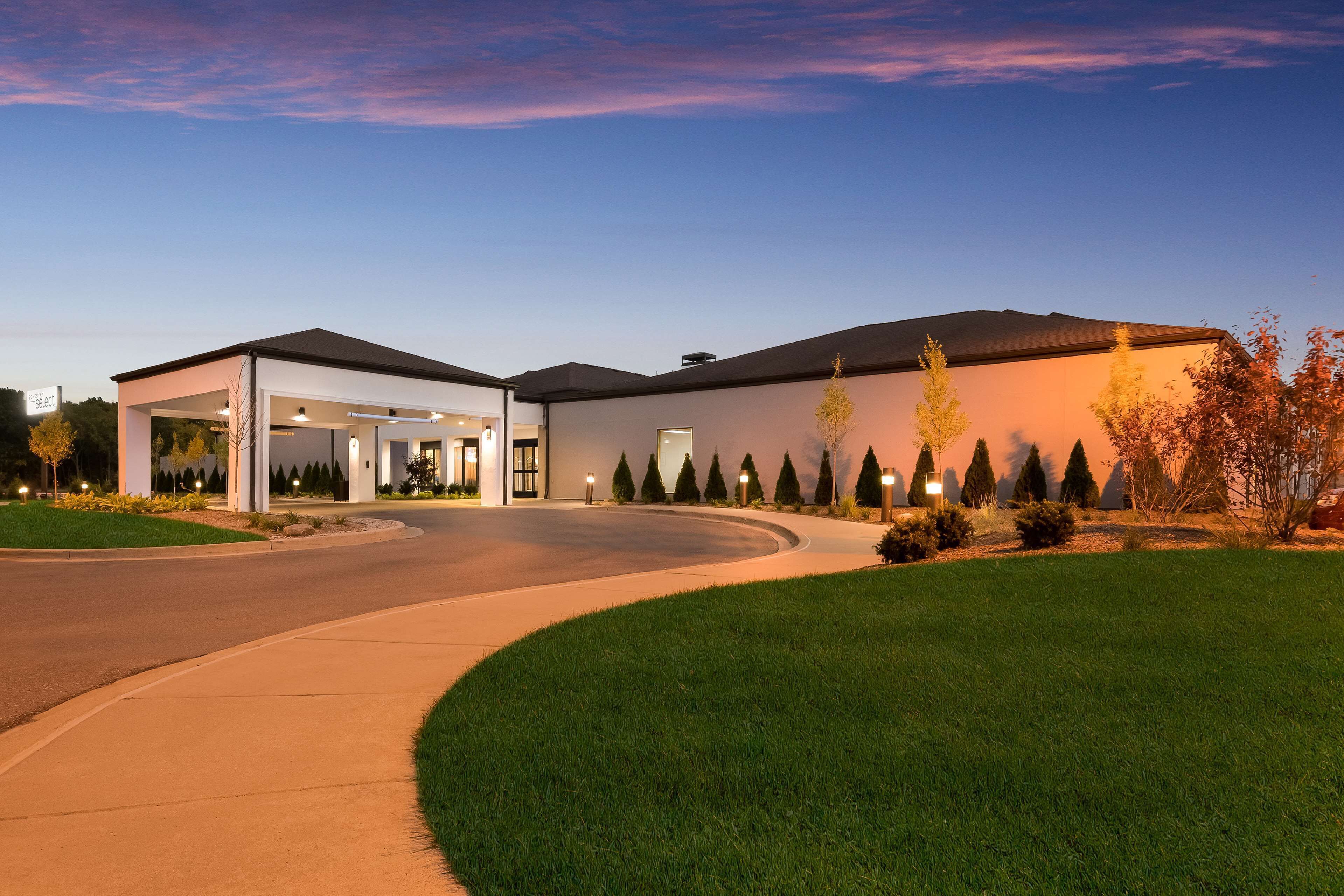 A modern building with a covered parking area and a well-maintained lawn.