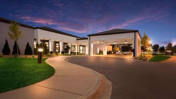 A modern building with a curved driveway, multiple entry points, and well-lit exterior. - Sonesta Select Detroit Auburn Hills (Auburn Hills)