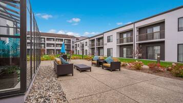 A courtyard with outdoor seating, a garden, and a building with balconies.