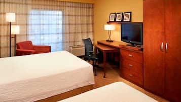 Een hotelkamer met twee bedden, een bureau met televisie, een stoel en een kledingkast.