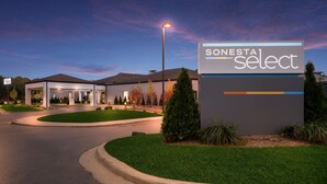 A modern hotel entrance with a sign reading "SONESTA Select" and a well-maintained lawn area. - Sonesta Select Detroit Auburn Hills (Auburn Hills)