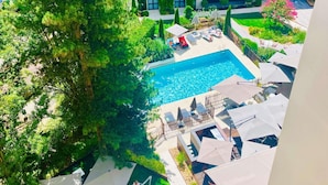 A rooftop pool area with lounge chairs and umbrellas, surrounded by lush greenery and a modern building with a glass facade. - Mercure Dijon Centre Clemenceau (Dijon)