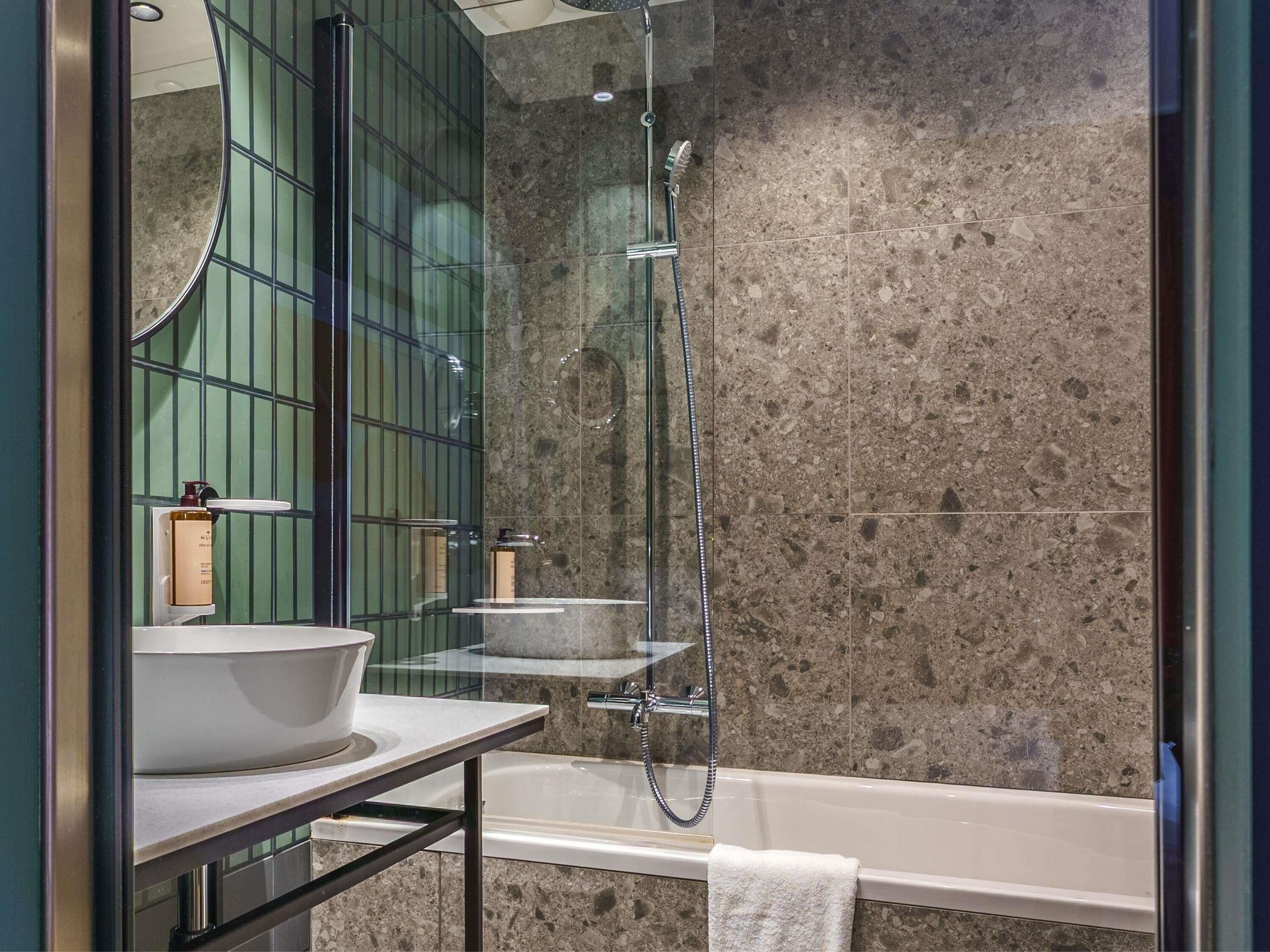 A modern bathroom with a freestanding bathtub, a large mirror, and a glass-enclosed shower area.