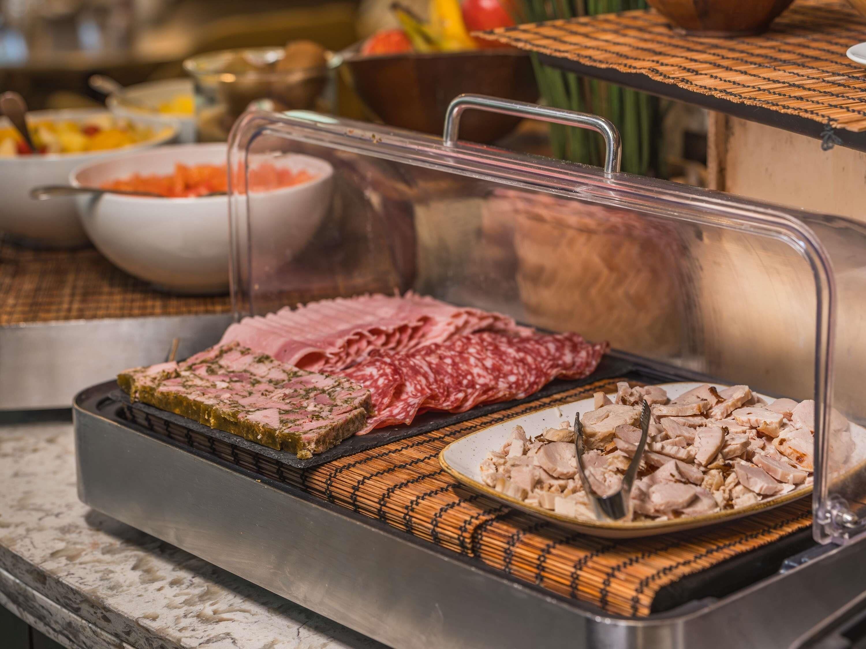 Buffet com diversos tipos de carne e uma saladeira de frutas.