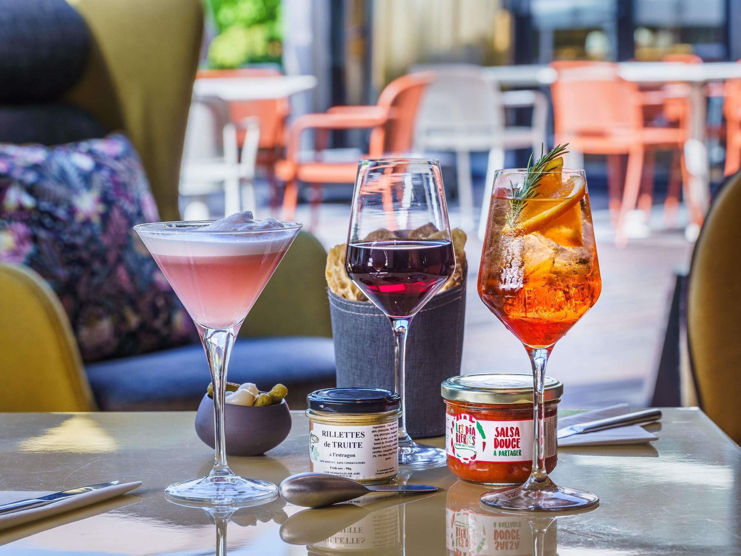 Une table avec trois boissons, un pot de confiture et une cuillère.