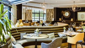 A modern restaurant with a curved seating area, large windows, and contemporary lighting fixtures. - Mercure Dijon Centre Clemenceau (Dijon)