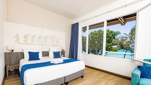 Een hotelkamer met een groot bed, uitzicht op het landschap en een bank.