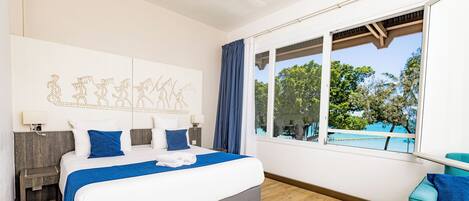 A hotel room with a large bed, a view of the outdoors, and a sofa.