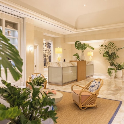 A spacious lobby with a reception desk, seating area, and potted plants.