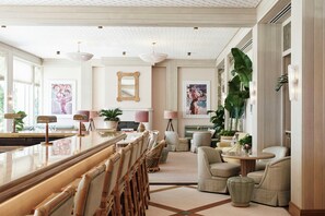 A spacious living area with a long bar, comfortable seating, and large windows.