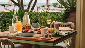A table set for breakfast with a view of the beach and umbrellas. - Four Seasons Resort Palm Beach (Palm Beach)