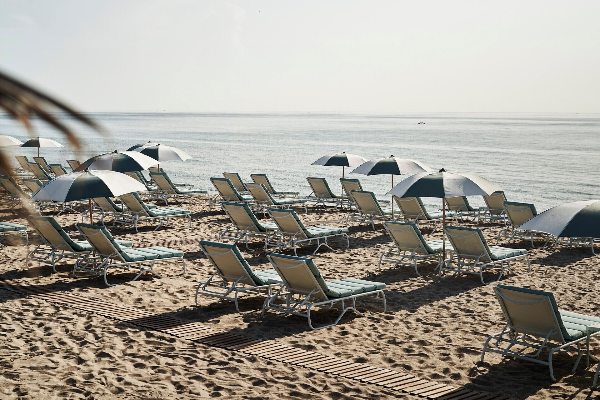 Am Strand, weißer Sandstrand, Liegestühle, Sonnenschirme