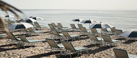 På stranden, hvit sand, solsenger og parasoller