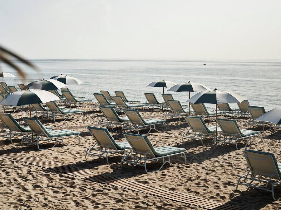 Am Strand, weißer Sandstrand, Liegestühle, Sonnenschirme