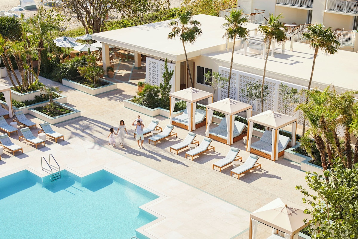 A pool area with sun loungers and a clear blue pool.