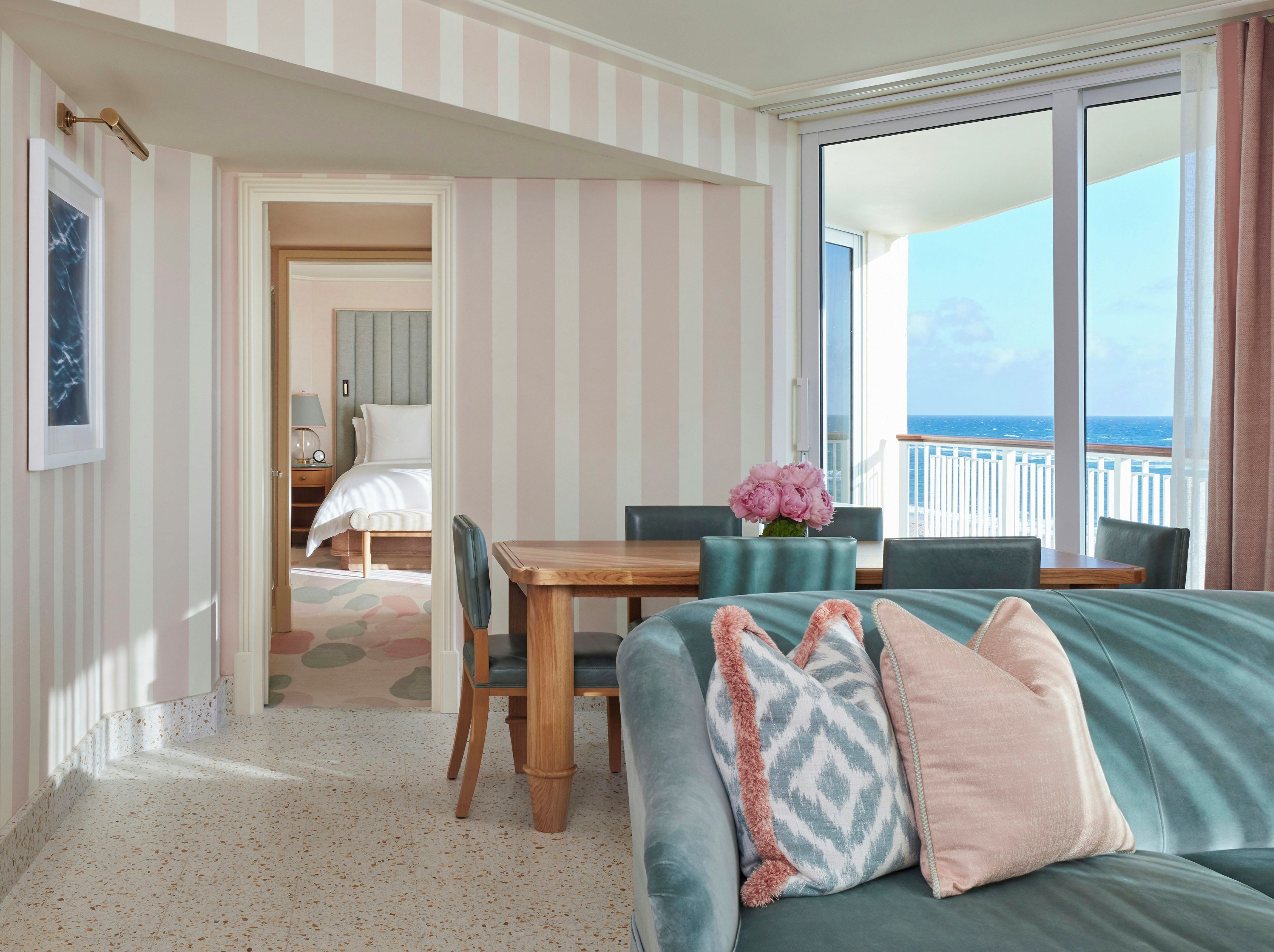 A hotel room with a balcony, a dining area, and a bed.