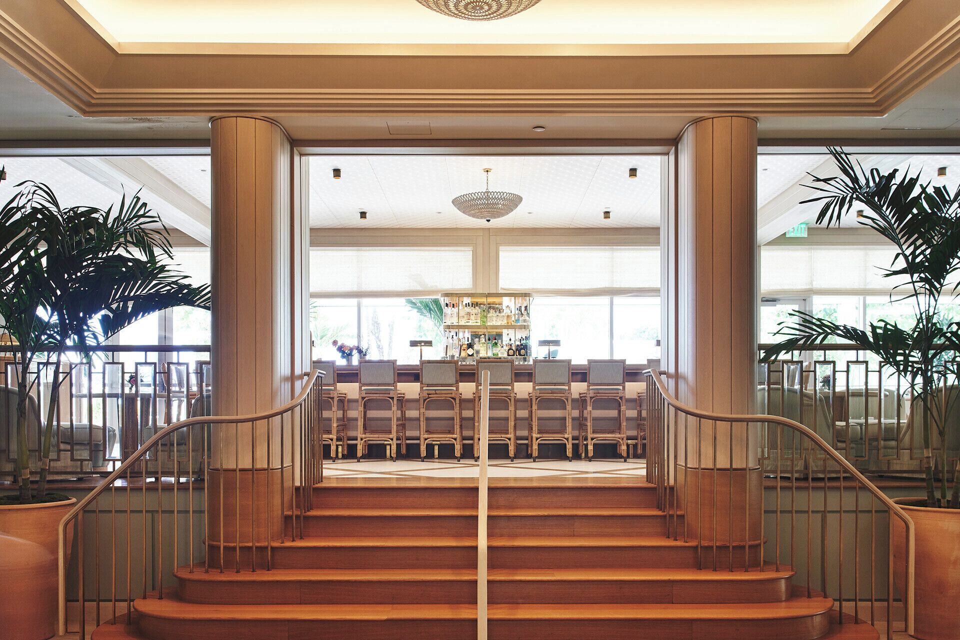 A grand staircase leading to a bar area with a high ceiling and large windows.